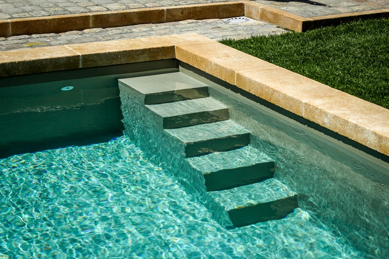L'escalier de la piscine nous fait plonger dans une eau émeraude. Le bassin est sublimé par ses margelles en pierre jaune épaisse